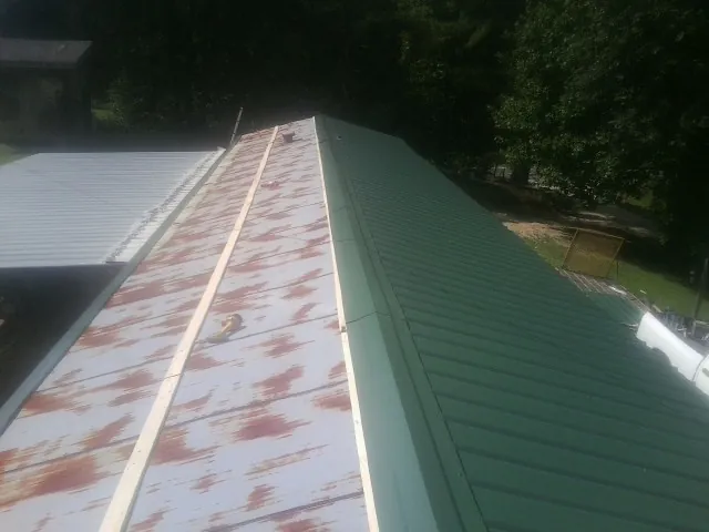 Old rusted panels beside newly installed green metal roofing — Wind Damage Roof Repair by Roofing Brothers in Oakmont
