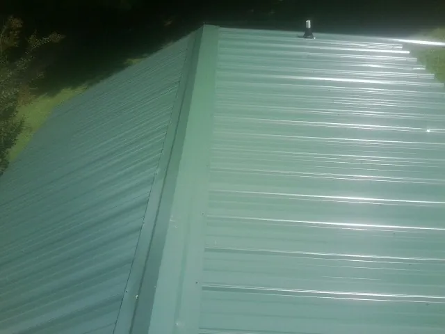 New green metal panels meeting at the ridge of a roof — Flat Roof Repair work by our crew in Oakmont