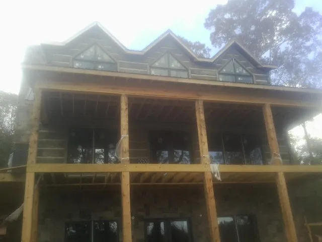 Dormers and porch framing on a large log home under construction — Roof Coating work by our crew in Oakmont