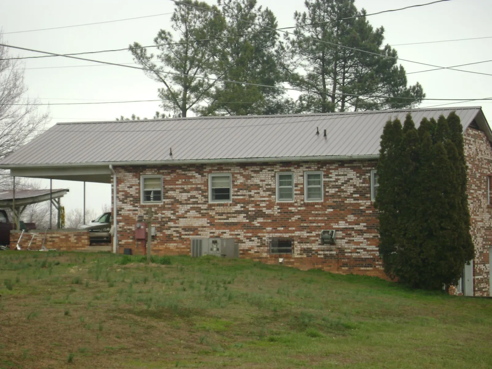 Gray metal roof on a brick split level home with a carport in Oakmont