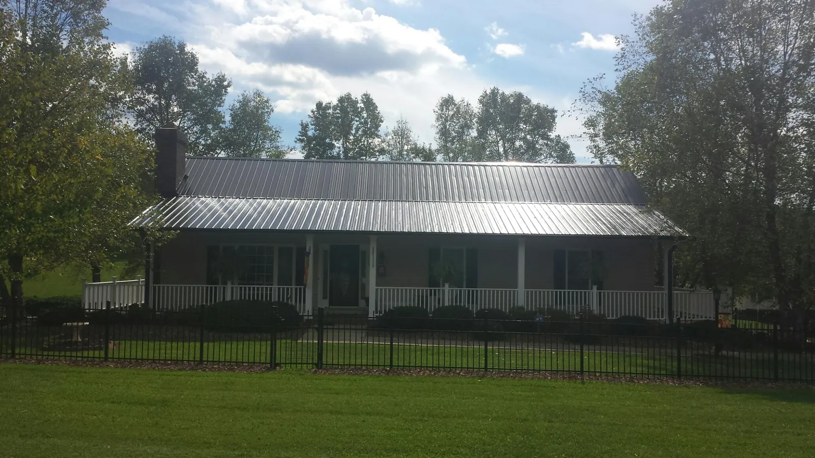 Gray metal roof on a brick ranch with a full width front porch — Gutter Guard Installation work by our crew in Oakmont