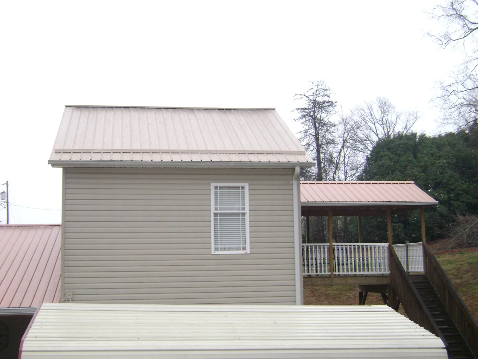 Tan metal roofs on a two story addition and attached porch, from a Roof Replacement job in Oakmont