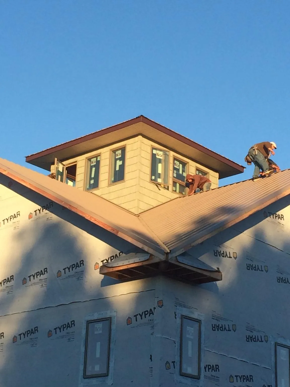 Roofers working around a rooftop cupola on a new metal roof at sunset — Roof Waterproofing in Oakmont by Roofing Brothers
